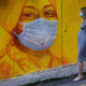 A pregnant woman wearing a face mask walks past a street mural in Hong Kong, on March 23, 2020,